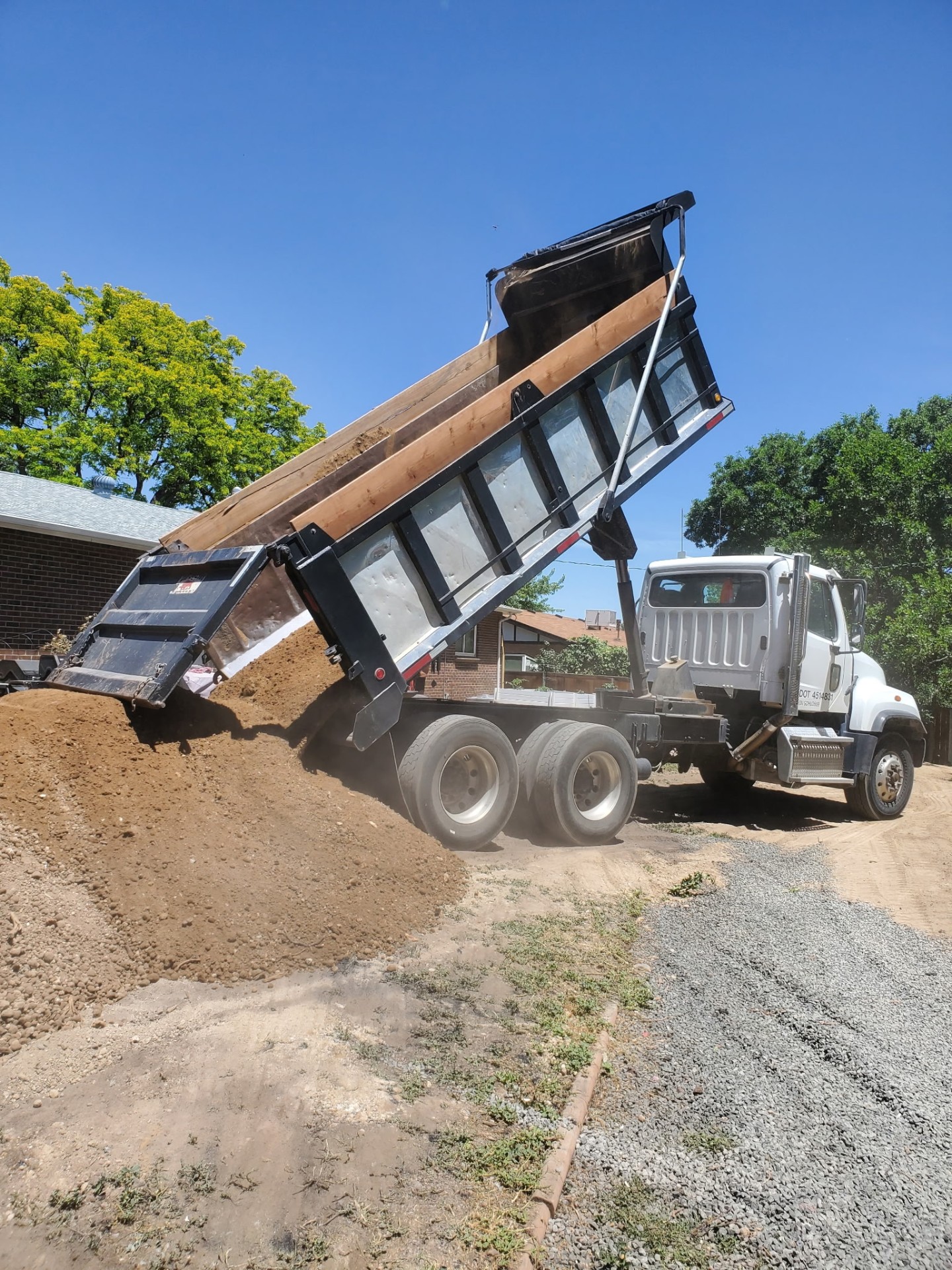 Aerial view of an orange skid steer grading a dirt lot with curved track marks.